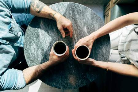 Photograph of two individuals having coffee, viewed from above the table. Photo by Joshua Ness on Unsplash.