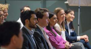 row of young professionals listening to someone speak