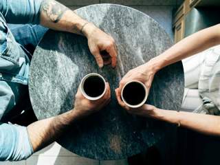 Photograph of two individuals having coffee, viewed from above the table. Photo by Joshua Ness on Unsplash.